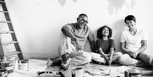 father son and mother sitting on the floor taking a break from painting walls inside their home