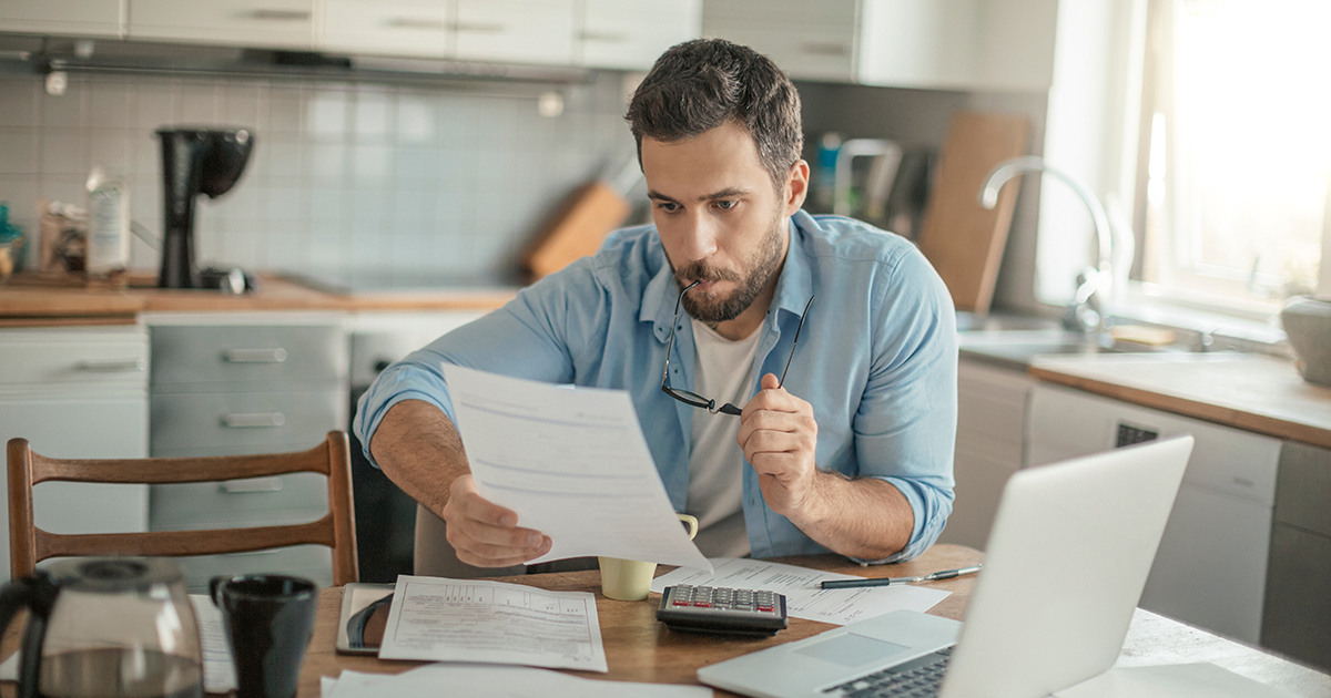 man looking at paperwork and laptop