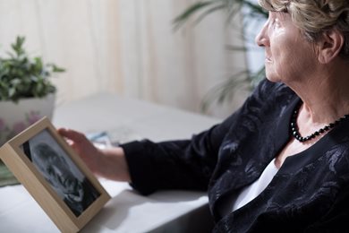 widow gazing sadly at a photo of her late husband