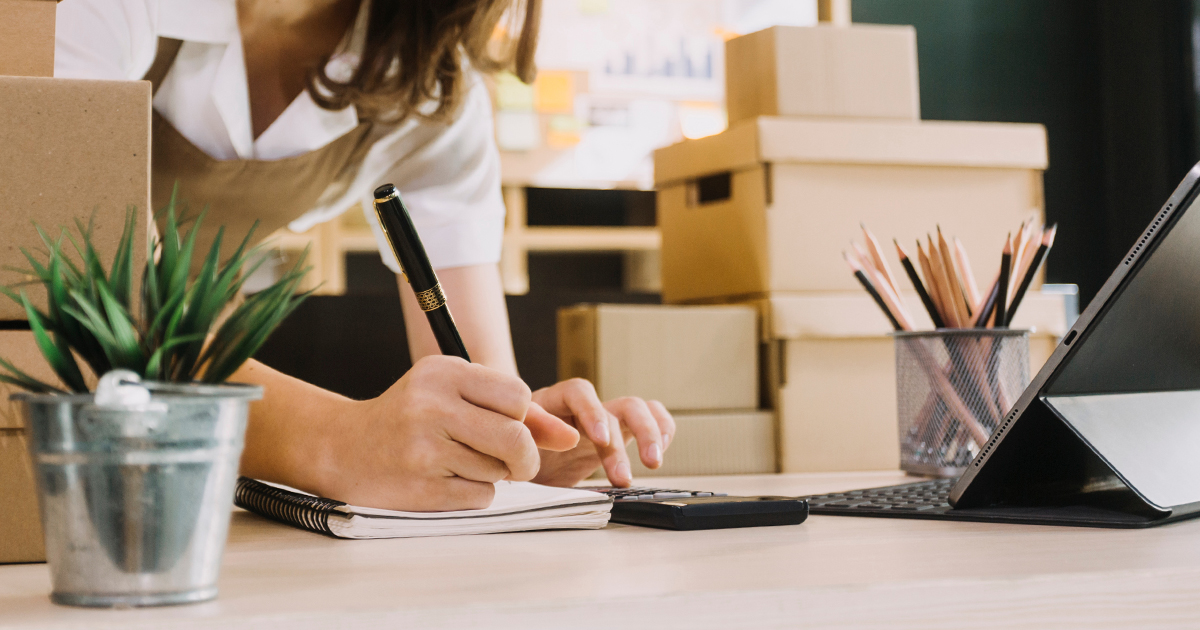 woman writing in notebook with calculator