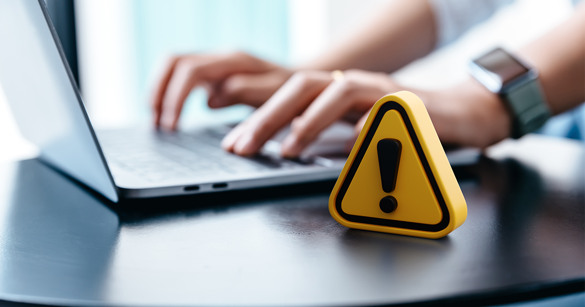 person on laptop with yellow security symbol