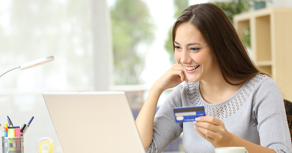 student looking at computer with debit card