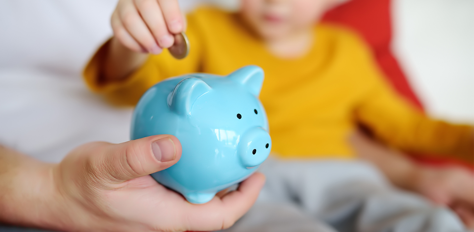 child putting coin into piggy bank