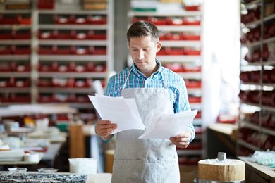 man looking at papers in a factory