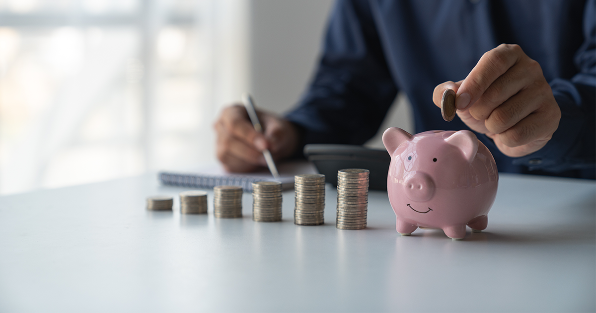 person with stack of coins and piggy bank