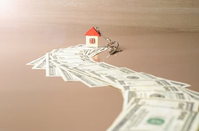 money lined up to a house keychain and key on table