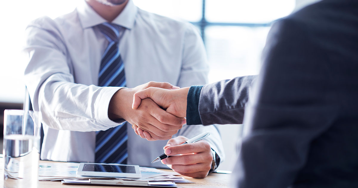 businessmen shaking hands at desk
