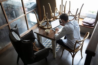 business owner using laptop in closed restaurant