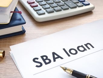 SBA loan documents, calculator and pen on desk