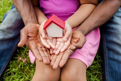 father and daughter holding a miniature house in their hands