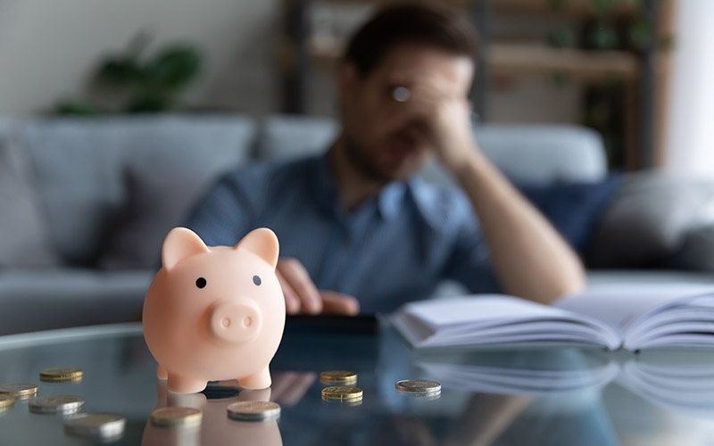 person looking stressed about finances with piggy bank
