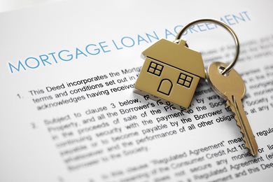 home keychain and key on mortgage loan agreement paperwork