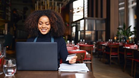 Woman sitting on her laptop holding a credit card