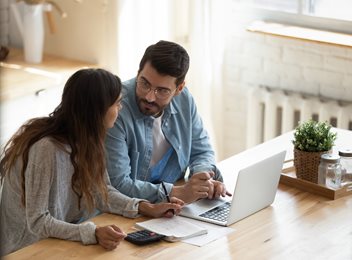 two people sitting at desk on laptop