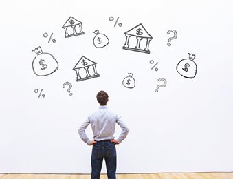 man looking at wall with drawn banks, question marks and percent symbols