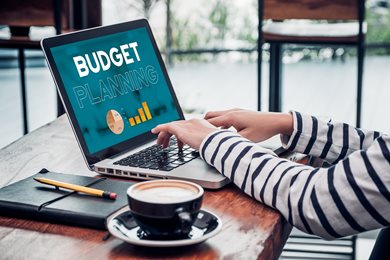 person at desk on laptop displaying "budget planning"